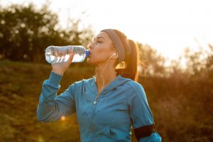 young athletic woman drinking water with her eyes closed while having water break morning run nature